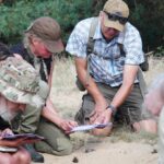 Deelnemers met een informatieschrift die meedoen aan een Workshop Wolvensporen gegeven door Weylin Tracking.